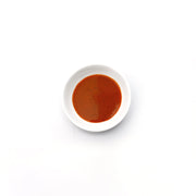 Small white bowl with red sauce on a white background