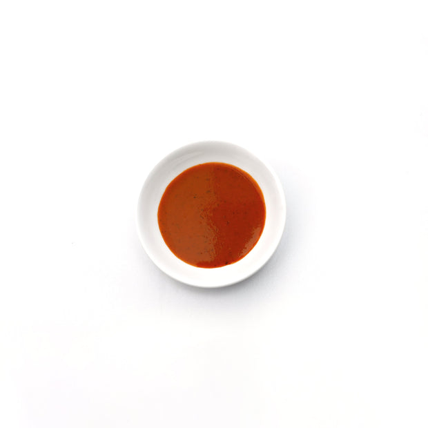 Small white bowl with red sauce on a white background