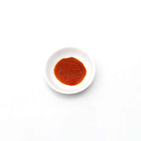 Small white bowl with red sauce on a white background