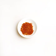 Small white plate with red spice on a white background