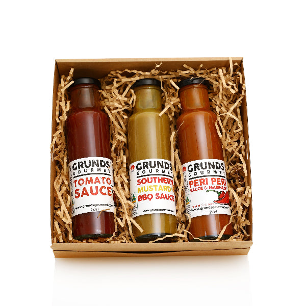 Three bottles of Grunds Gourmet sauces in a box with straw padding on a white background