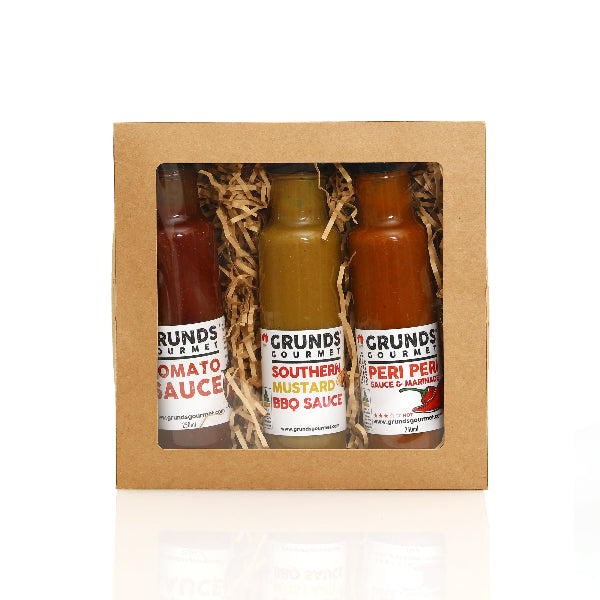 Three bottles of Grunds Gourmet sauces in a cardboard gift box on a white background