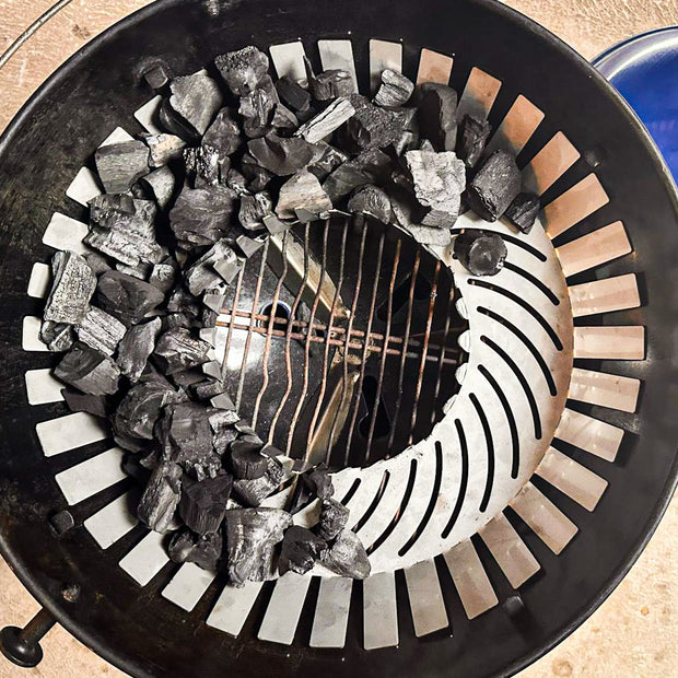Barbecue grill with charcoal and a blue lid on a beige surface