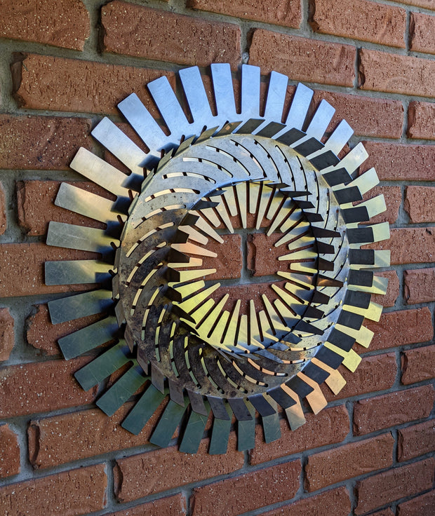 Decorative metal wall art with a spiral design on a brick wall