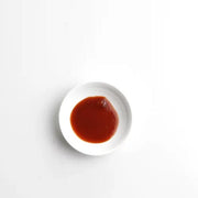 Small white plate with red sauce on a light gray background