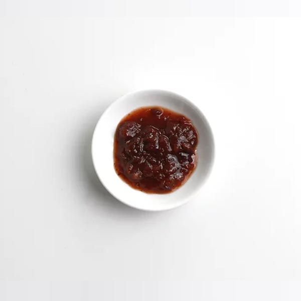 Small white bowl with dark brown sauce on a light gray background