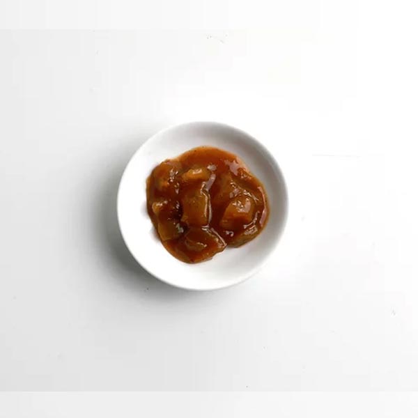 Small white plate with a serving of brown sauce on a light gray background