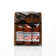 Three bottles of Grund's Gourmet Chilli Sauce in a clear package on a white background