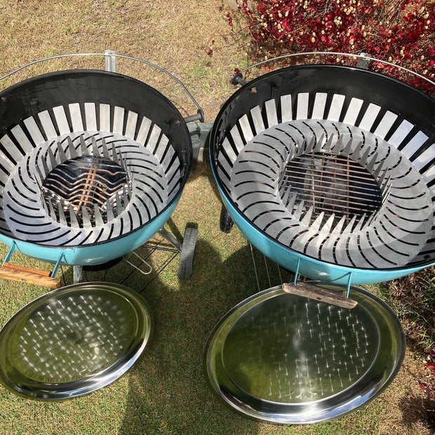 Two charcoal grills on a grassy surface with a blurred background