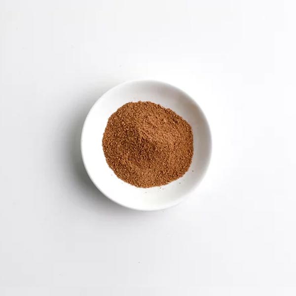 White bowl with brown powder on a light gray background
