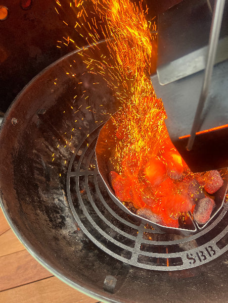 Hot coals and glowing embers in a barbecue grill with sparks flying.