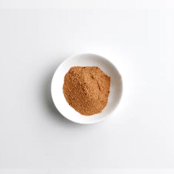 Brown powder in a white bowl on a light gray background