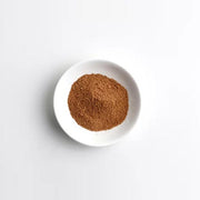 White bowl with brown powder on a light gray background