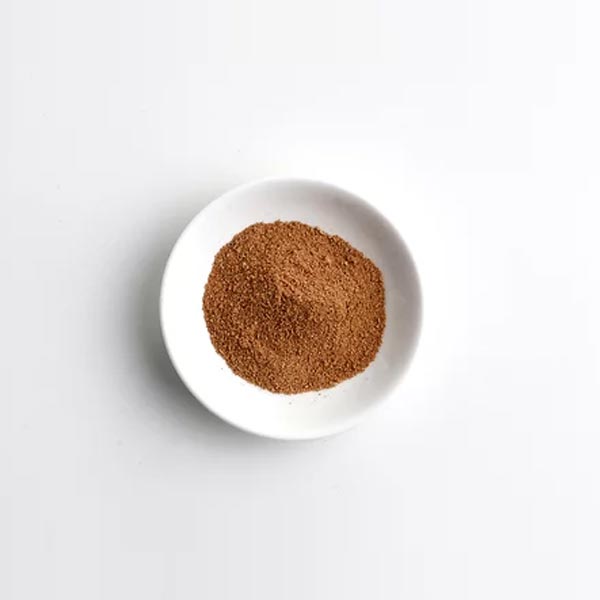 White bowl with brown powder on a light gray background