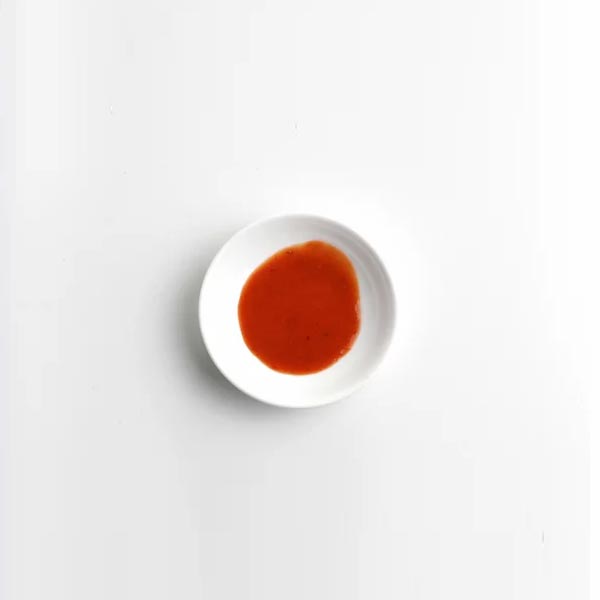 Red sauce on a white plate against a light gray background