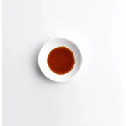 White plate with a small amount of brown liquid on a white background