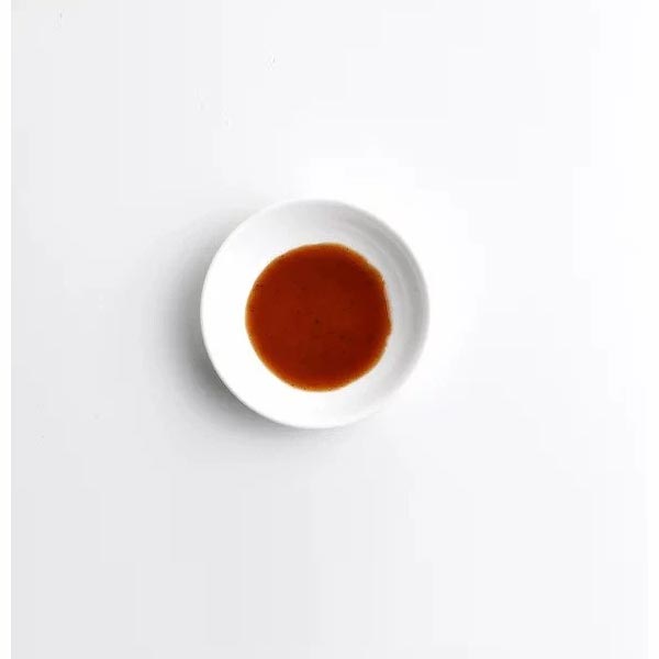 White plate with a small amount of brown liquid on a white background