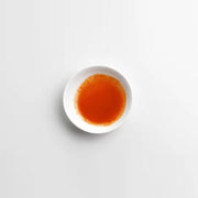 Small white dish with red sauce on a light gray background